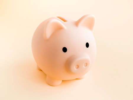 Cute piggy bank, pink color isolated on soft beige background. Saving money, Investment and finance concept.の写真素材