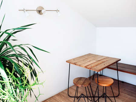 Empty wooden table with round chairs on wooden floor with wall lamp decoration in the corner of...
