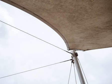 Steel wire rope supporting at pull points connection on the pole of old white outdoor canvas roof on sky background with copy space.の写真素材