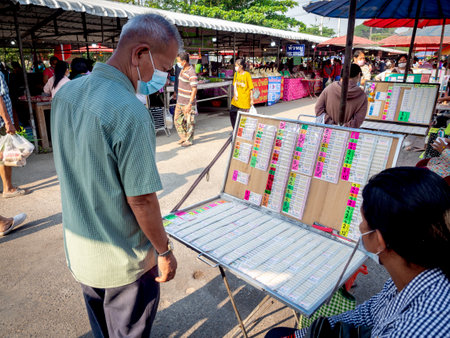 February 27, 2020 - Nakhon Sawan, Thailand: People looking and choosing numbers from Thai lottery tickets in shop in local market.のeditorial素材