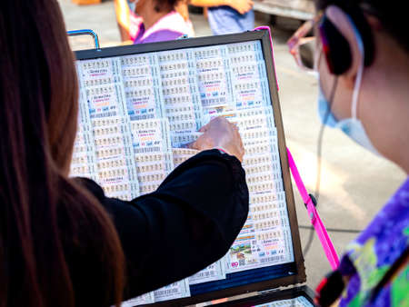 February 27, 2020 - Nakhon Sawan, Thailand: Woman's hand choosing Thai lottery tickets from the shop...