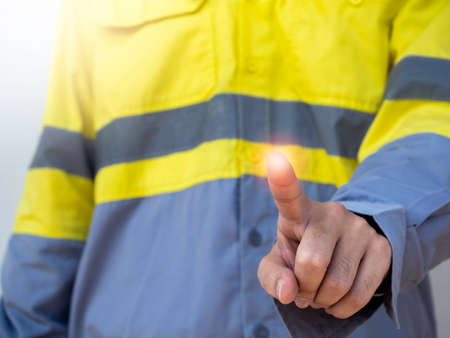 Success shining light on finger. Closeup engineering people wearing yellow high visibility jacket pointing finger with blank space for text or copy. Work safety concept.の写真素材