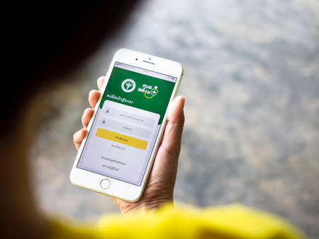 NAKHON SAWAN, THAILAND - May 2, 2021: "Mohpromtâ application from Thai government for Thai people to register for booking for the coronavirus vaccination. Hand holding mobile phone with app on screen.のeditorial素材