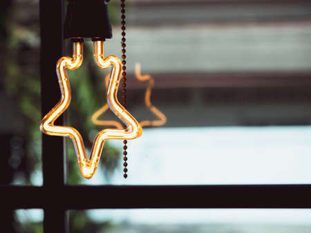 Star shape light bulb decoration in cafe. LED lamp retro style shining near the glass window with copy space.の写真素材