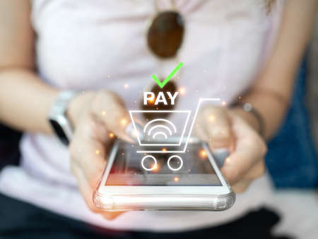 Online shopping concept. Contactless pay with mobile phone. Close-up woman's hand using smartphone...