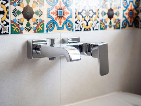 Close-up modern stainless steel faucets for bathtub near beautiful moroccan style mosaics tiles background.の写真素材