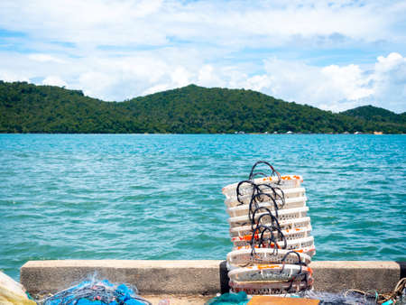 Piles of empty white fisherman baskets to be dried in the sun at the dock of fisherman village on seascape and mountain background in Thailand with copy space.の写真素材
