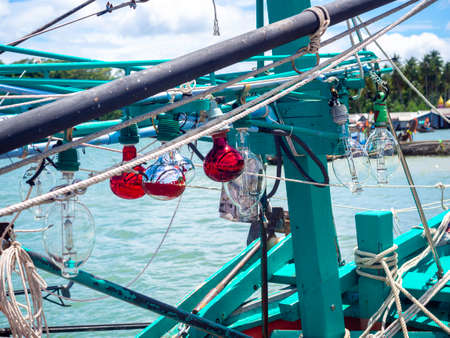 Light lamps and many messy ropes on wooden local fisherman boat at the dock of fisherman village on seascape background in Thailand.の写真素材