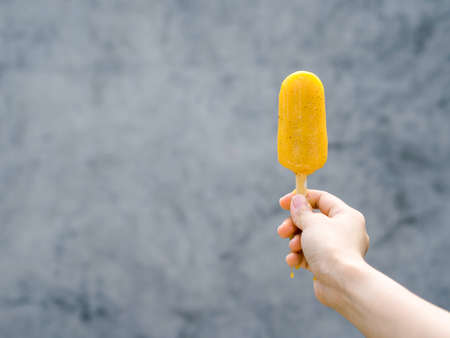 Close up yellow ice cream in womanâs handの写真素材