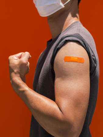 Vaccinations, bandage plaster on vaccinated people arm concept. The orange color adhesive bandage on...
