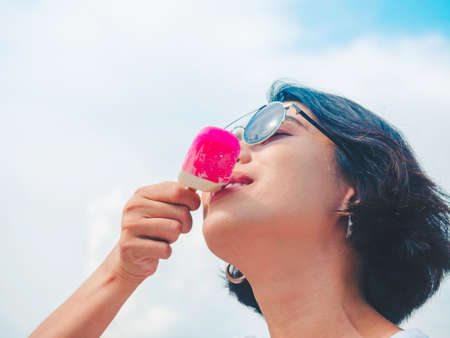 Smiling Asian woman short hair in casual white sleeveless shirt wearing sunglasses holding pink on...