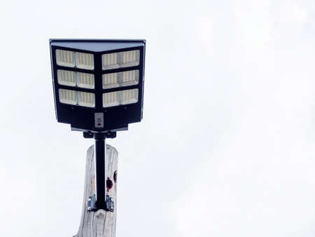 Solar light mounted on a wooden pole on blue sky background with copy space. Street lamp with solar panel, view from under.の写真素材