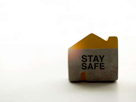 Stay safe concept. Words "Stay Safe" on small concrete house shape isolated on white background with copy space. Social media campaign for covid-19 or coronavirus pandemic prevention.の写真素材
