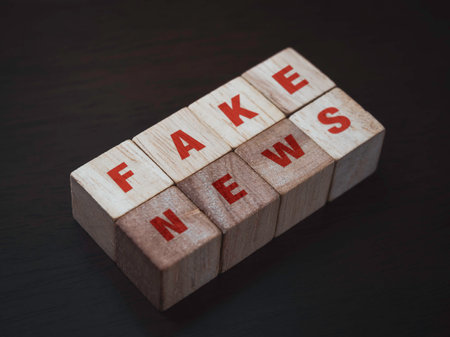 Fake news, red words on wooden cube block on dark background. Fake, discredit, lie, confusion, incite and distortion concept.の写真素材