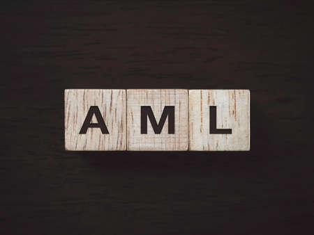 Anti Money Laundering Concept. Word AML on wooden blocks with on dark wooden background, top view....