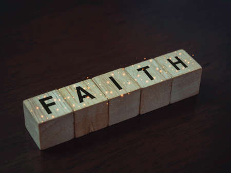 Faith, words on wooden cube blocks on dark brown wood background, close up.の写真素材
