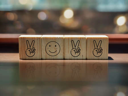 2022, new year start with positive concept, two fingers and smiling face icon as a year number on wooden cube blocks on brown wood desk and celebrate lighting bokeh background.の写真素材