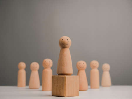 Leader woman, influencer, women in leadership position concept. Wooden figure, happy and strong female with smiling standing on the box and team, minimal style.の写真素材