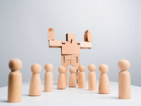 Leadership concept. The Leader or influencer, wooden robot strong power gesture standing among wood human, followers on white background, minimal style.の写真素材