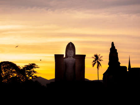 Amazing scenetic of silhouette of Wat Mahathat Temple in the precinct of Sukhothai Historical Park with big buddha statue on golden sunset sky background, a UNESCO World Heritage Site in Thailand.のeditorial素材