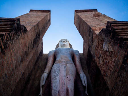 Amazing scene of big standing buddha statue and old ancient structure at Wat Mahathat Temple in the precinct of Sukhothai Historical Park, a UNESCO World Heritage Site in Thailand.のeditorial素材