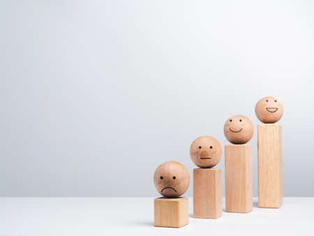 Satisfaction and business growth process and economic improvement concept. Emoticon, emotion faces wooden balls and wood cube blocks chart steps on white background with copy space, minimal style.の写真素材