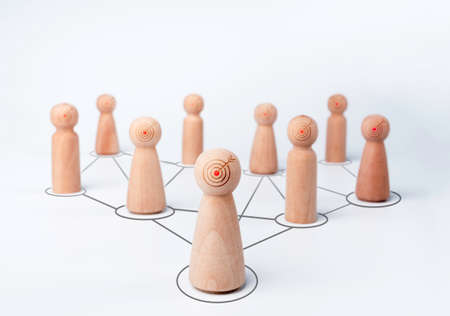 Leader woman, influencer, wooden figures with goal target icon on faces, standing in front of the team with connection symbol on white background, minimal style. Leadership, empowerment concept.の写真素材