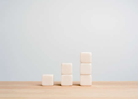 Growth and success business chart built with white blocks as steps on wood table, white background with copy space. Increase revenue, benefit, profit, and economic improvement concept.の写真素材