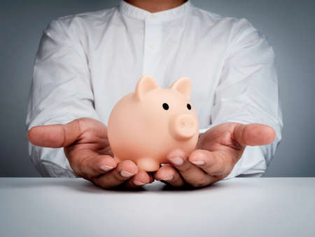 Saving money, financial, and business investment concept. Pink piggy bank is holding by...