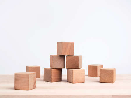 Empty wooden cube blocks on the table on white background with copy space. Many wood bricks building...