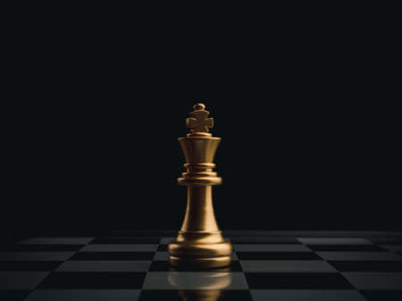 The golden king chess piece standing alone on chessboard on dark background. Leader, influencer, lonely, commander, strong, and business strategy concept.の写真素材