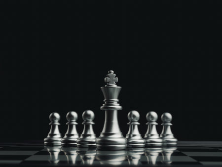 The silver king chess piece standing in front of pawn chess pieces on chessboard on dark background....