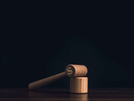 A wooden judge gavel with dollar money icon in the shadow with the soundboard with scales icon, toys on wooden table, dark background with copy space, minimal style. Injustice and corruption concept.の写真素材