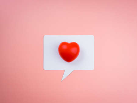 Like, social media icon with red heart ball on white speech bubble isolated on pink pastel background. Generic social media likes notifications. Love concept, minimal style.の写真素材