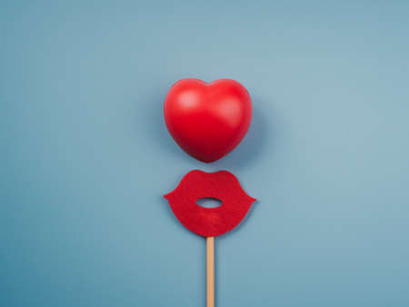 Red heart ball and red mouth on stick isolated on blue background, minimal style.