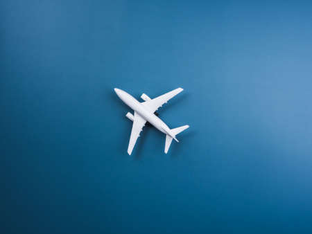 White plane toy model at the center on blue background, top view, minimal style. White airplane, flat lay design. Flight, travel concept.の写真素材