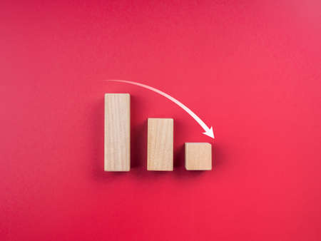 Graph trending downwards. Business crisis concept. Down arrow on three wooden blocks chart steps on...