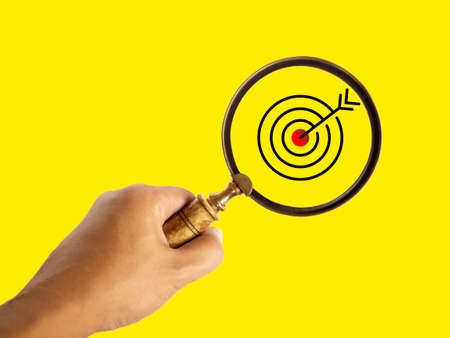 Target board, red bull's eye icon inside the magnifying glass in hand for focus business target on...