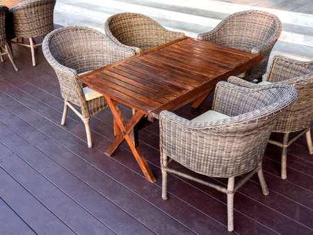 Empty rattan furniture, outdoor garden weave table set with wooden table and five chairs on the floor in the terrace near the steps in breakfast area at the resort.の写真素材