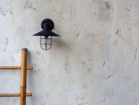 Empty space of white concrete wall texture background decoration with wall lamp and wooden bamboo ladder.の写真素材