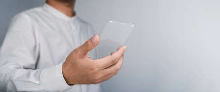 Future transparent glass phone Technology. Mock-up blank screen futuristic super slim transparent smartphone in business person hand with copy space. Future technology communication equipment.の写真素材