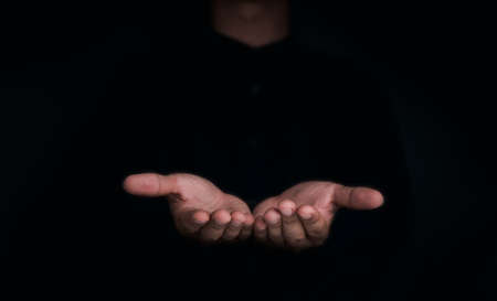 Give two hands with nothing on both on dark background with copy space. Close-up receiving gesture of outstretched cupped empty open hands. Concept of giving, donation, receiving, asking, and bribery.の写真素材