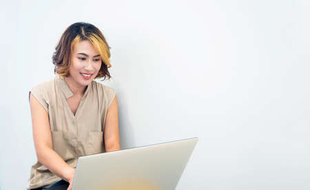 Asian woman, freelance with trendy short hair looking at the screen while working with laptop...