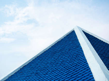 Arrangement of blue house roof tiles in white cement edge frame on the top on blue sky background with copy space.の写真素材