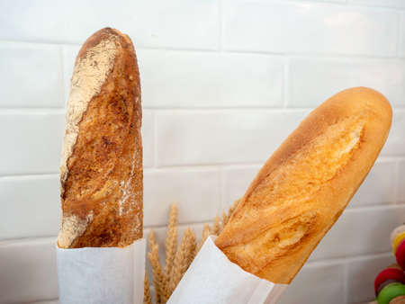 Close-up two original french baguettes bread wrapped with papers on white wall background.の写真素材