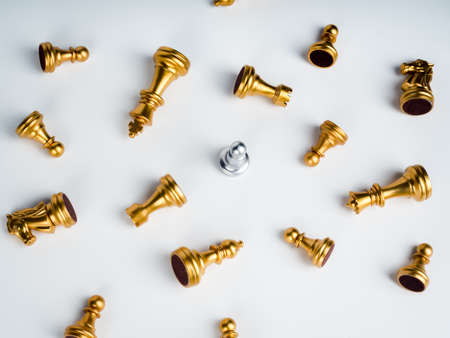 A silver pawn chess piece standing alone in the middle of many fallen silver pawn chess pieces on white background. Stand out from the crowd. Leadership, Unique, survivor, winner, difference concept.の写真素材
