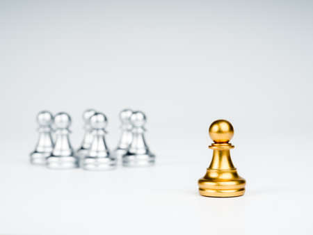 The golden pawn chess piece standing out from the group of silver pawn chess pieces on white...