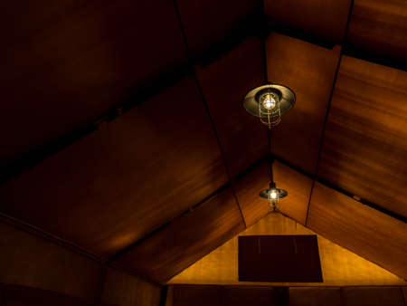 Old retro style lamp hanging on the ceiling inside the large glamping tent at a night with copy space. Lighting in the tent.の写真素材