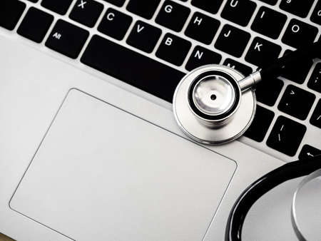 Close up stethoscope on keyboard and touchpad on laptop computer background with copy space, top view. Business, technology, healthcare and medical, fix and repair concept.の写真素材