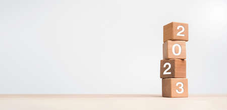 2023 Happy New year background banner. Two thousand Twenty-Three year numbers on wooden cube blocks stack on white background with copy space. Welcome, Merry Christmas, and Happy New Year in 2023.の写真素材